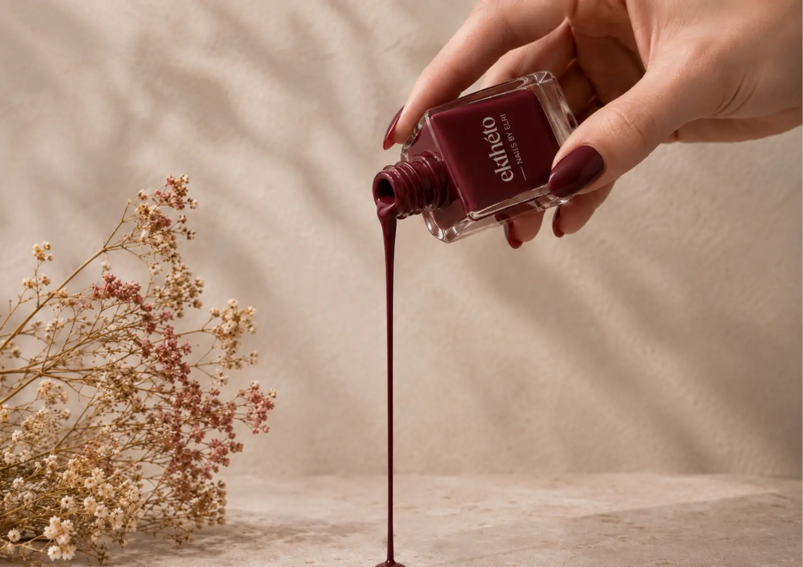 Burgundy nail polish beside delicate wildflowers